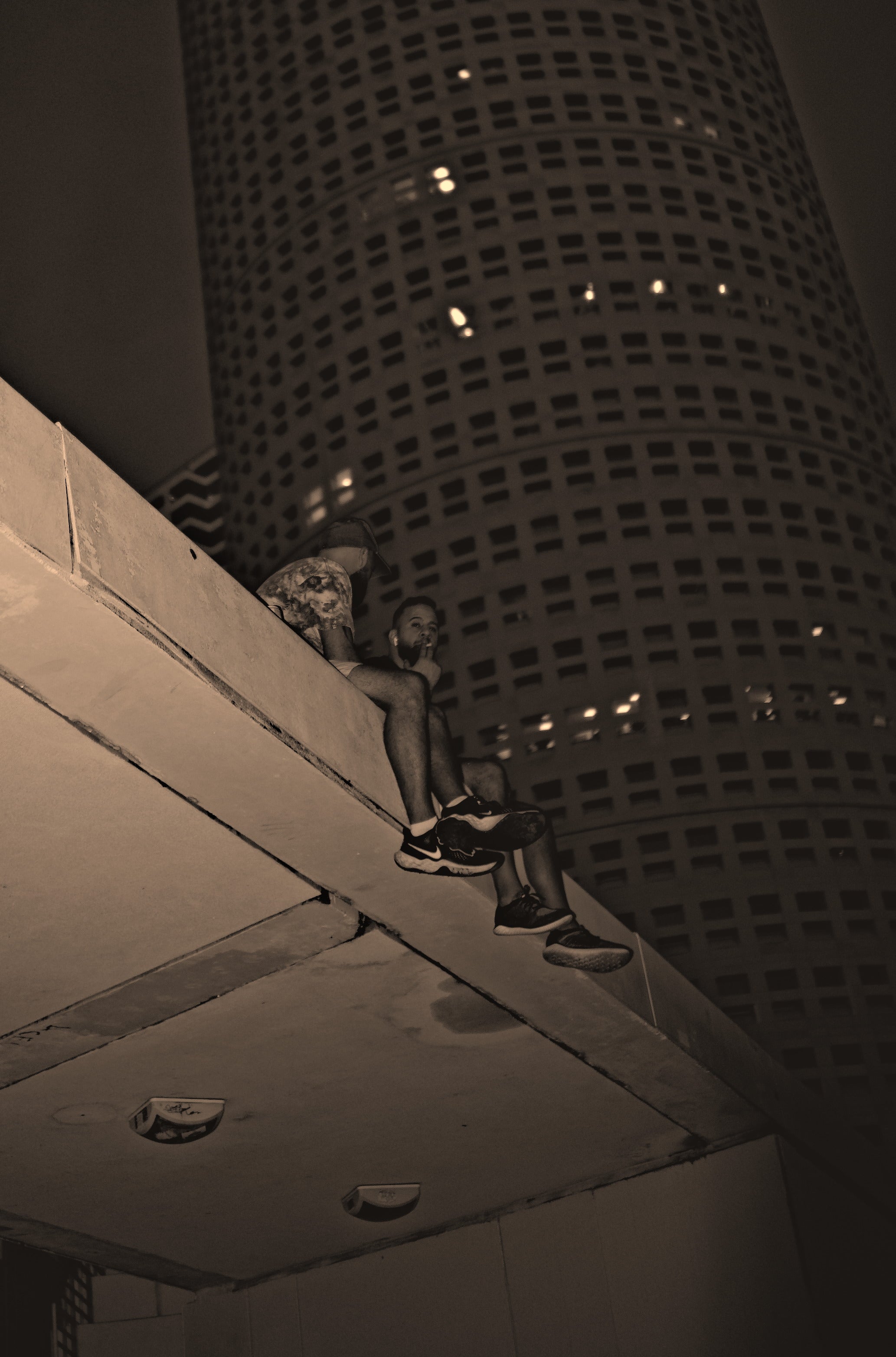 Person sitting on a ledge with a tall building in the background. Acacia Cinematography, Tampa, Fl 